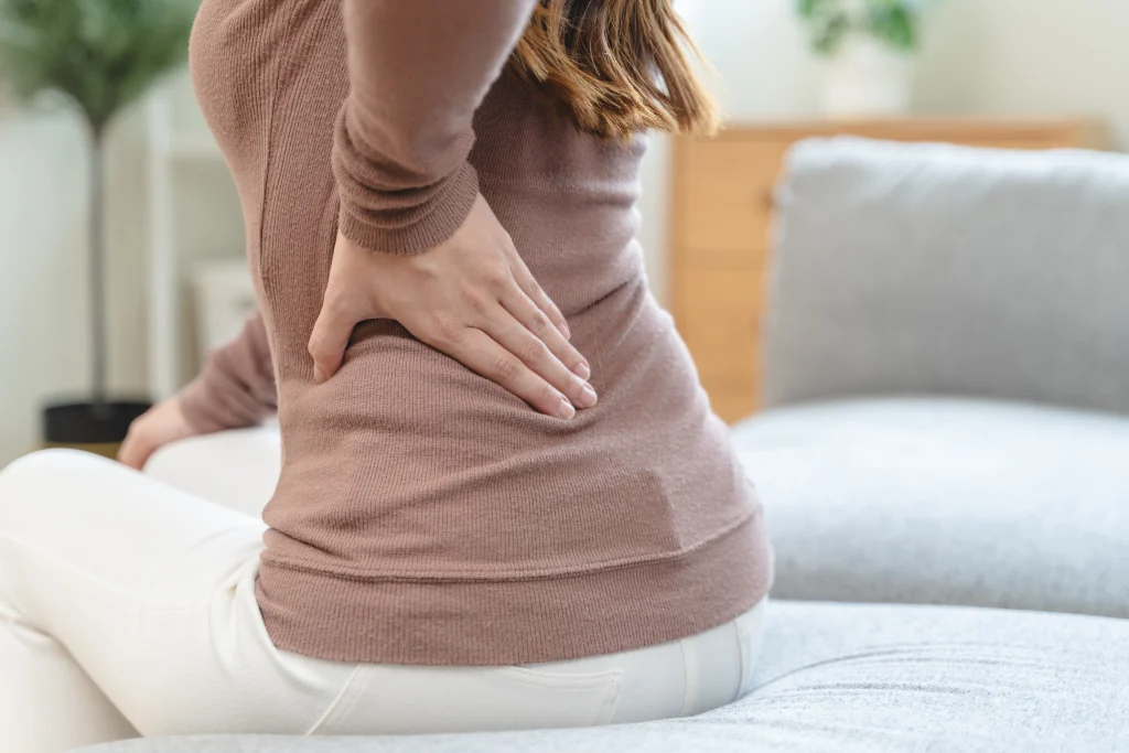 female touching her back suffering from muscle pain from sitting position during work.